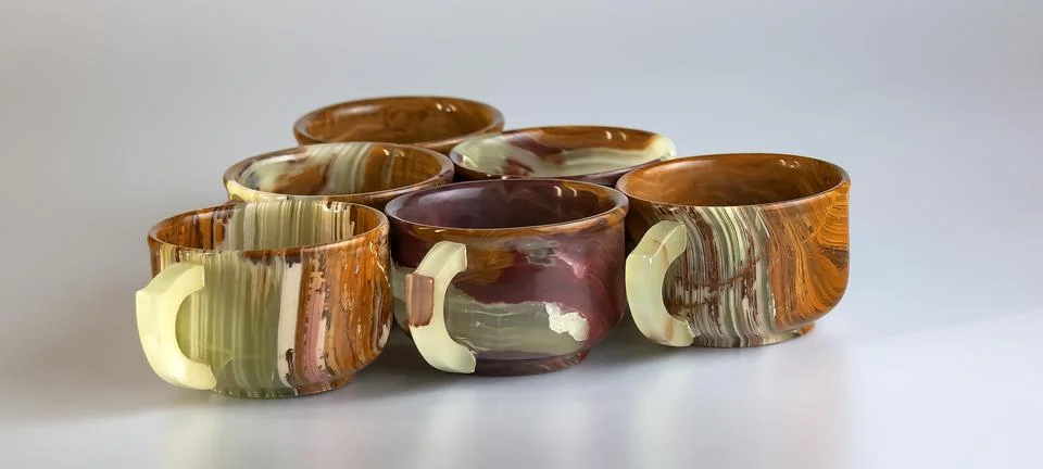 Empty cups made of multi-colored onyx in yellow-orange tones on a white bac.. Stock Photos