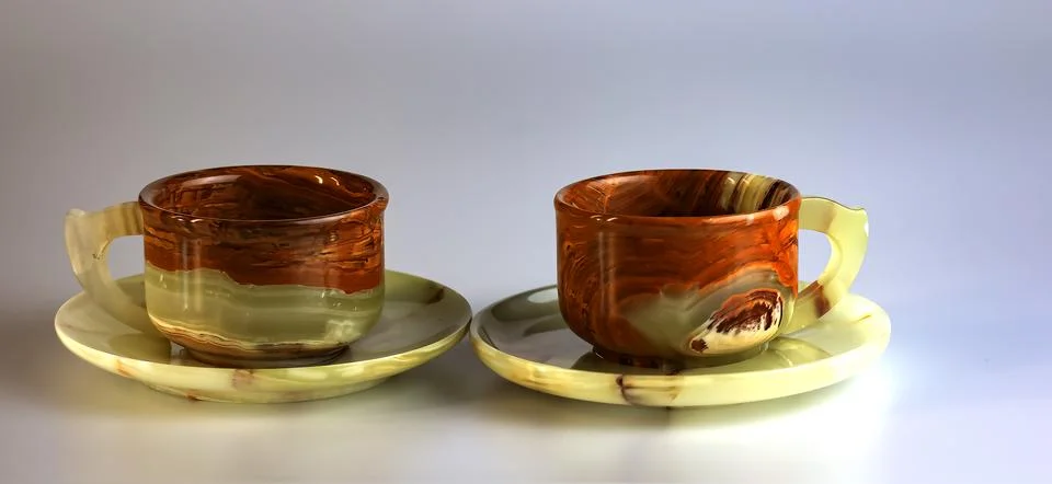 Empty cups made of multi-colored onyx in yellow-orange tones on a white bac.. Stock Photos