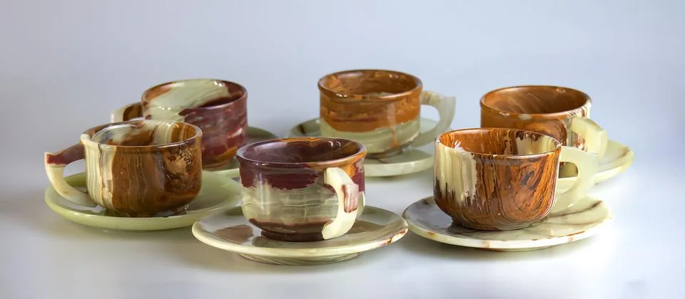 Empty cups made of multi-colored onyx in yellow-orange tones on a white bac.. Stock Photos