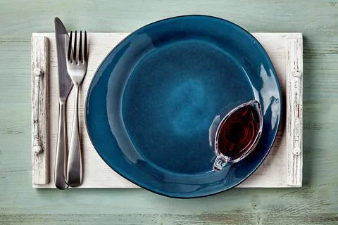 Empty dark blue ceramic plate with berry sauce in a gravy boat Stock Photos