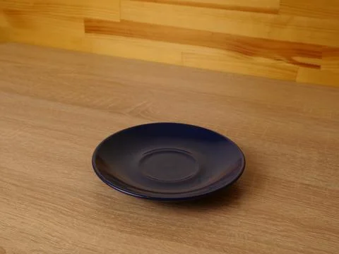 Empty dark blue glossy ceramic saucer placed on a wooden countertop against a Stock Photos