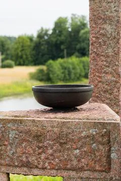 Empty dark ceramic bowl on stone pedestal. Minimalist pottery vessel outdoo.. Фото