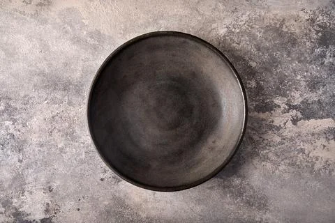 Empty dark deep plate on gray textured background as concrete. Copy space Stock Photos