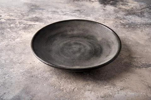Empty dark deep plate on gray textured background as concrete. Copy space Stock Photos