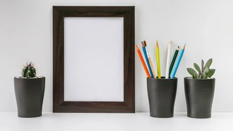 Empty dark photo frame, two succulents in dark pots and colored pencils on a  Foto stock