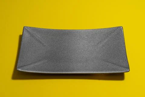 Empty dark plate on yellow background Stock Photos