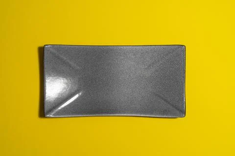 Empty dark plate on yellow background Stock Photos