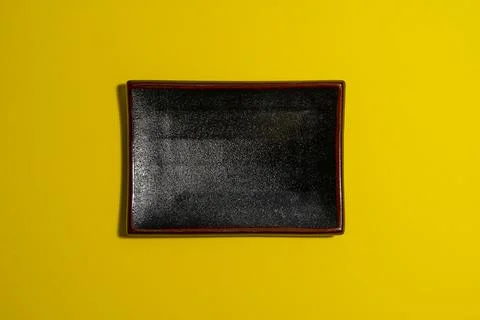 Empty dark plate on yellow background Stock Photos