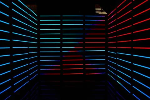 Empty dark room lined with red and blue LED horizontal poles of light Foto stock
