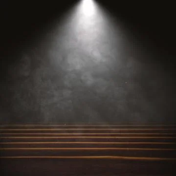 Empty dark wooden stage with a bright spotlight shining through smoke and m.. Stock Photos