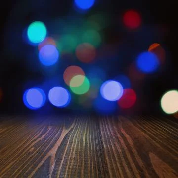 Empty dark wooden table surface with vibrant blurred bokeh lights backgroun.. Stock Photos