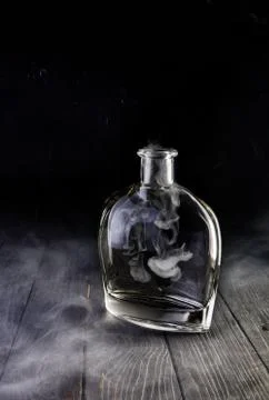 Empty decanter with smoke on black background Stock Photos