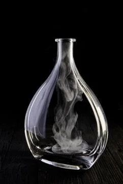 Empty decanter with smoke on black background Stock Photos