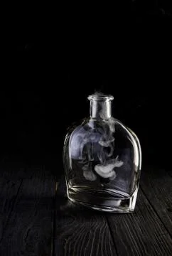 Empty decanter with smoke on black background Stock Photos