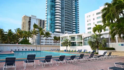 Empty deck chairs stand around the outdoor swimming pool. Lounge area in the Stock Footage 333212509