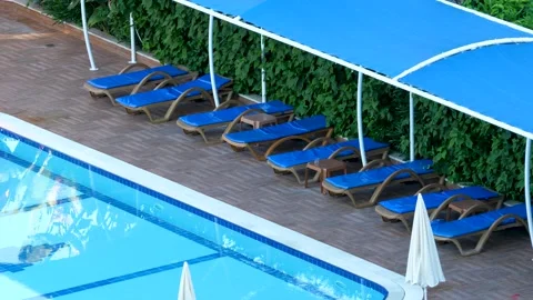 Empty deckchairs, pool and water surface Stock Footage 164941123