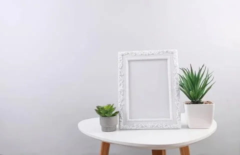 Empty decorative frame with potted plants on white table Stock Photos