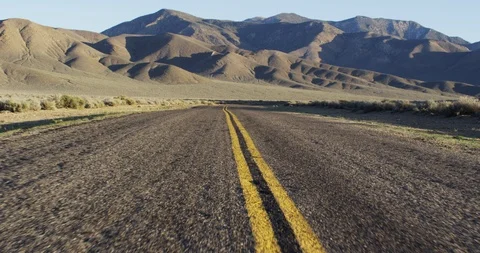 Empty desert road with mountains on a sunny day Stock Footage 107628093