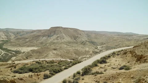 Empty desert winding road on hot sunny day during summer with mountain and dunes Stock Footage 240538619