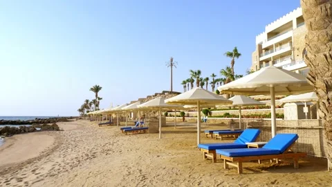 Empty, deserted beach with palm trees, sun loungers and umbrellas of an Stock Footage 136895329