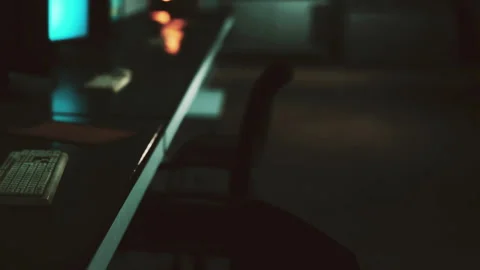 Empty desk in a dimly lit room with a computer and chair Stock Footage 344967496