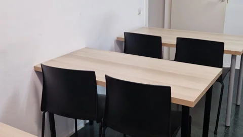 Empty desks and black chairs inside a bright classroom at a language school Stock Footage 345176824