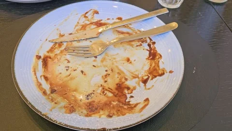 Empty dessert plate after eating a chocolate waffle, with fork and knife Stock Footage 335220392