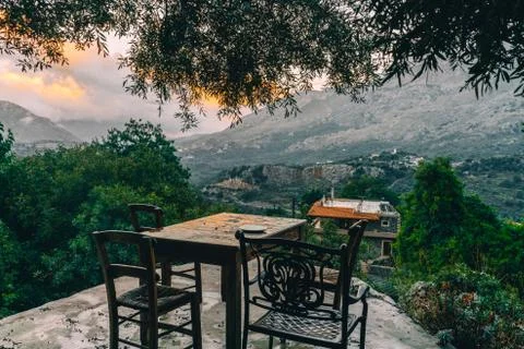 Empty dining table with chairs overlooking mountains with low hanging clouds and Foto stock