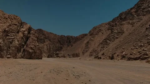 Empty dirt road disappearing into rugged mountains, symbolizing resilience Stock Footage 346244942