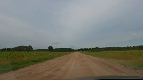 Empty dirt road stretching through rural grassland under wide cloudy sky with Stock Footage 345453259