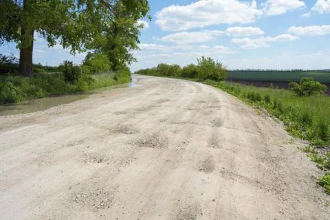 An empty dirt road through a green landscape under a clear sky, dirt road, Stock Photos