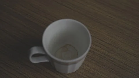 Empty dirty coffee cup placed on wooden table with banana peel thrown nearby Video stock 278936215