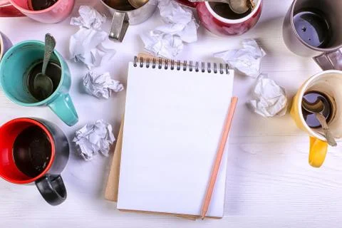 Empty dirty coffee cups, different colors on the table and a notebook for wri Stock Photos