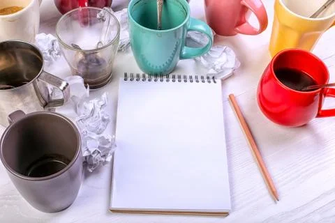Empty dirty coffee cups, different colors on the table and a notebook for wri Stock Photos
