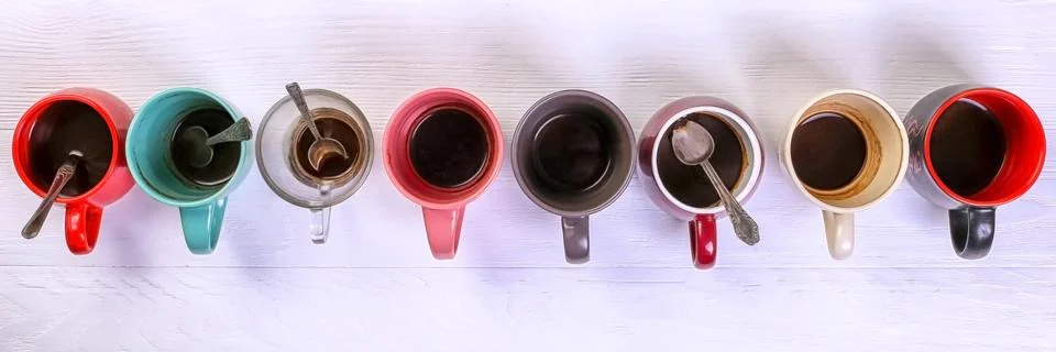 Empty dirty coffee cups of different colors on the table. Concept of caffeine Stock Photos