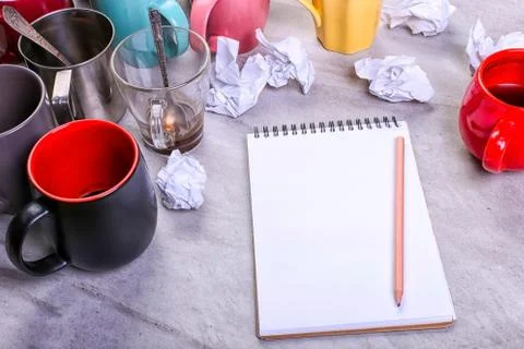 Empty dirty coffee cups, different colors on the table and a notebook for wri Stock Photos
