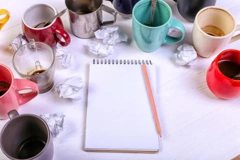 Empty dirty coffee cups, different colors on the table and a notebook for wri Stock Photos