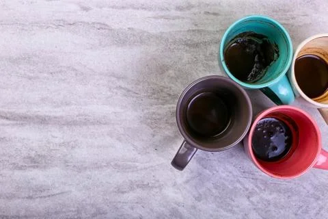 Empty dirty coffee cups of different colors on the table. Concept of caffeine Stock Photos