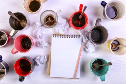 Empty dirty coffee cups, different colors on the table and a notebook for wri Stock Photos