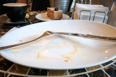 Empty dirty dish with fork and knife left on table Stock Photos
