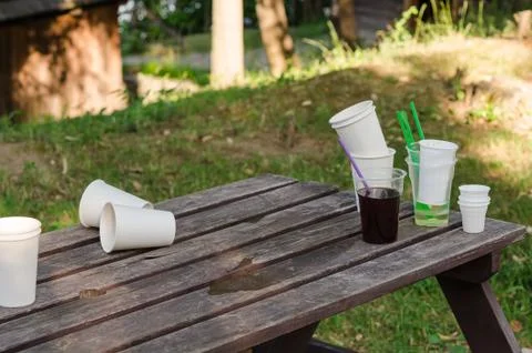 Empty dirty plastic and disposable cups, left on a wooden table Stock Photos