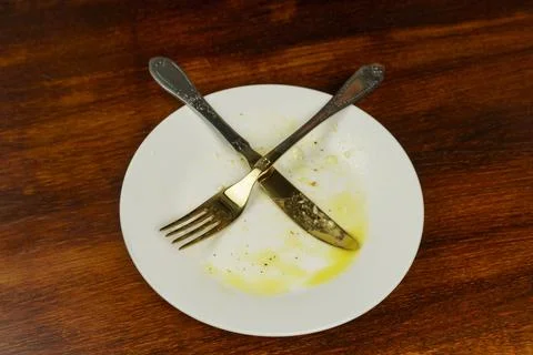 Empty dirty plate with fork and knife. Empty plate after dinner. Stock Photos
