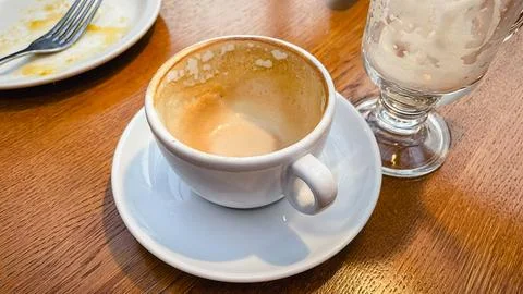 Empty dirty white cup and saucer on a wooden table after drinking coffee in.. Stock Photos