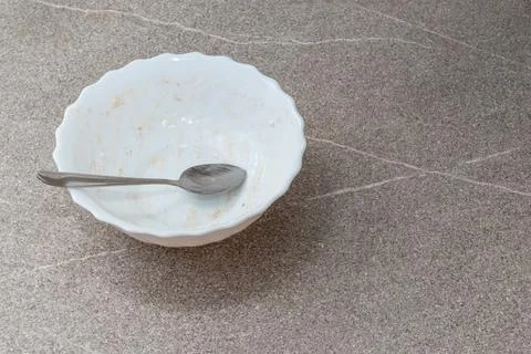 Empty dirty white plate with some crumbs and a spoon on gray cement backgroun Stock Photos