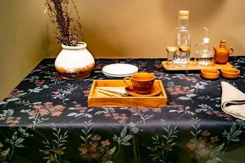 Empty dishes are on the table on a black flowered tablecloth Stock Photos