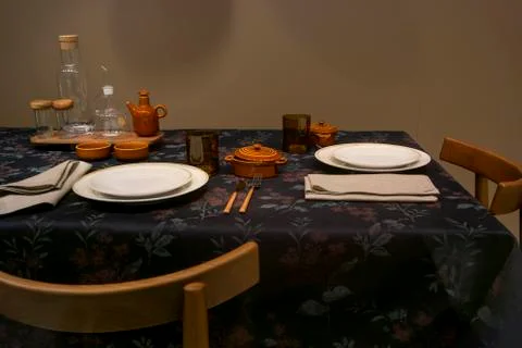 Empty dishes are on the table on a black flowered tablecloth Stock Photos