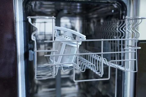 Empty dishwasher in the kitchen. Dishwasher filter. Stock Photos