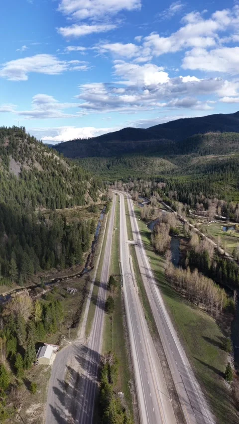 Empty divided highway winds through forested mountain valley near Haugan Stock Footage 340968861