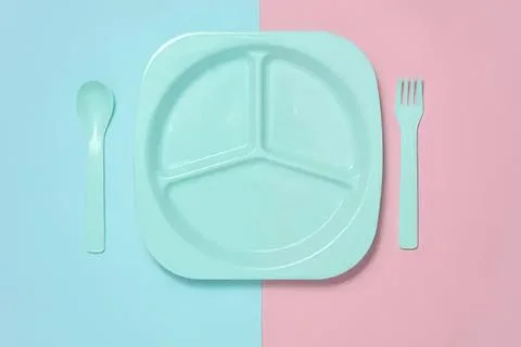 Empty divided plate with spoon and fork on pastel background Stock Photos