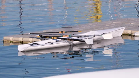 Empty double scull rowing boat moored to a floating  on blue water Stock Footage 344684926